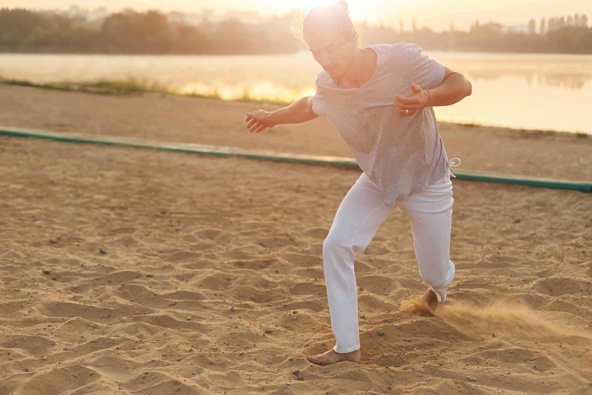 Athletic capoeira performer making movements on the beach