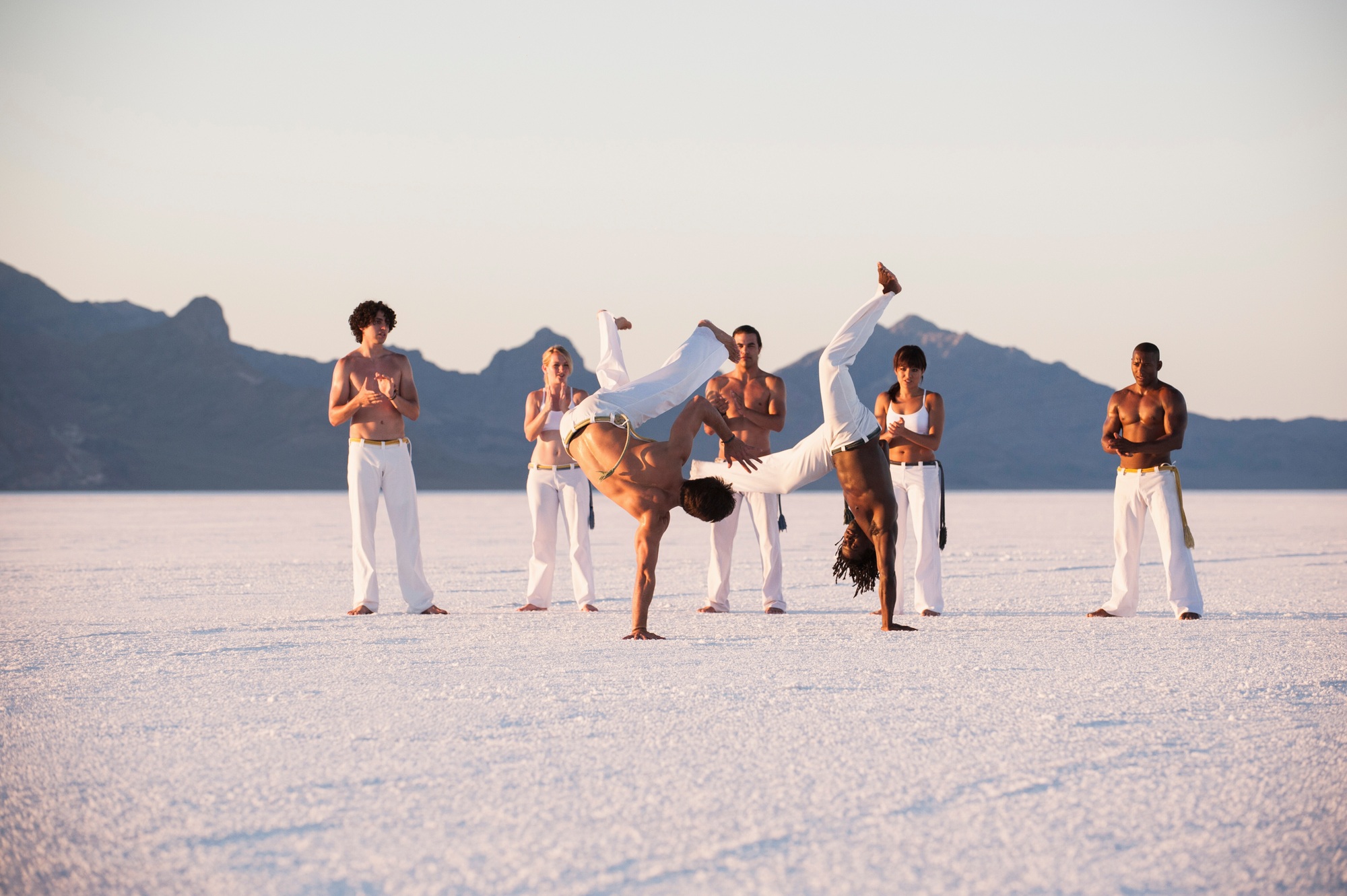 Team clapping man performing capoeira on Bonneville Salt Flats, Utah, USA